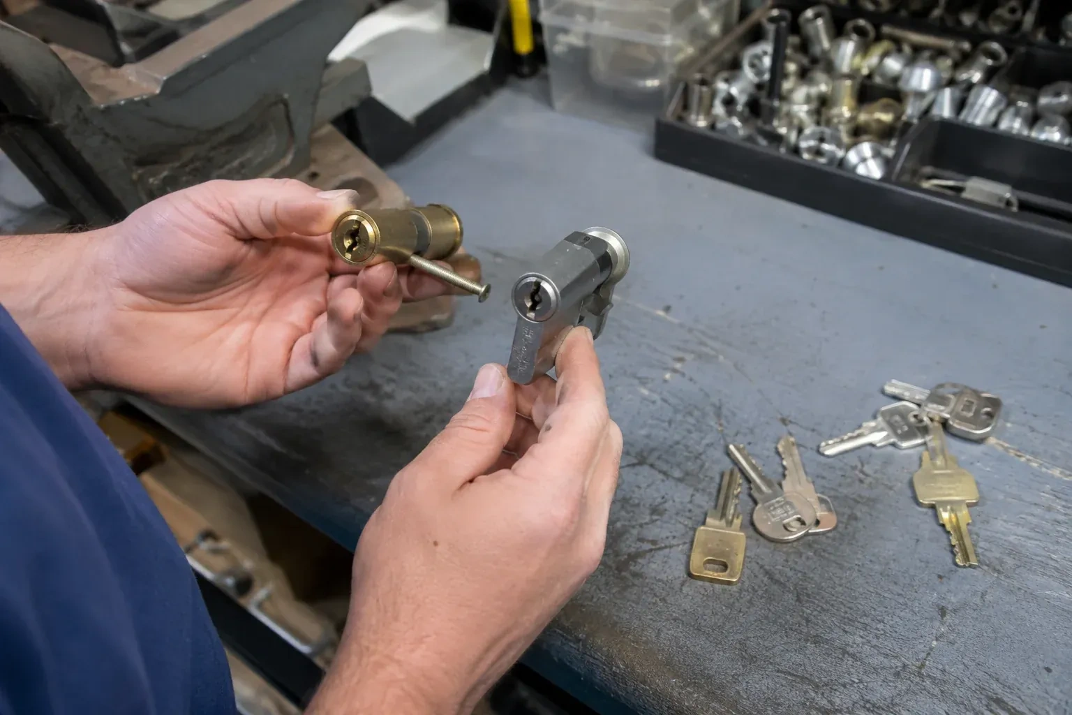 Hands comparing detached lock cylinders beside loose keys on a workbench. — Broken Key Extraction, Peterborough